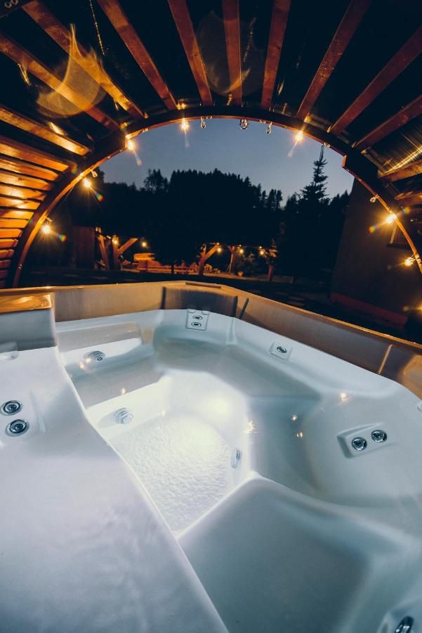 Jacuzzi pod drewnianym zadaszeniem po zmroku